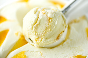 Vanilla ice cream scoop background. Summer food concept, copy space, top view. Scooped texture. Scooping out yellow mango ice-cream.