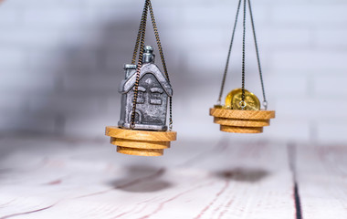 Stack of coins and a small house on the scales. The concept of choice, cash savings and purchase of real estate.