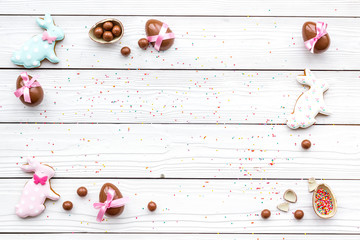 Celebrate Easter. Modern signs of Easter. Chocolate Easter eggs and Easter bunny cookies. White wooden background top view copy space