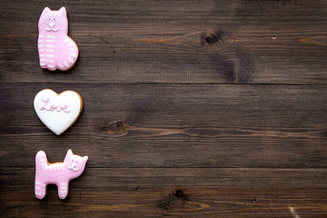 Valentine's Day candy. Heart shaped cookie with lettering Love and kitty on dark wooden background top view space for text