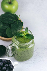 Healthy green smoothie in a glass jar and ingredients on white - spinach, apple and blueberry. Superfood, detox food