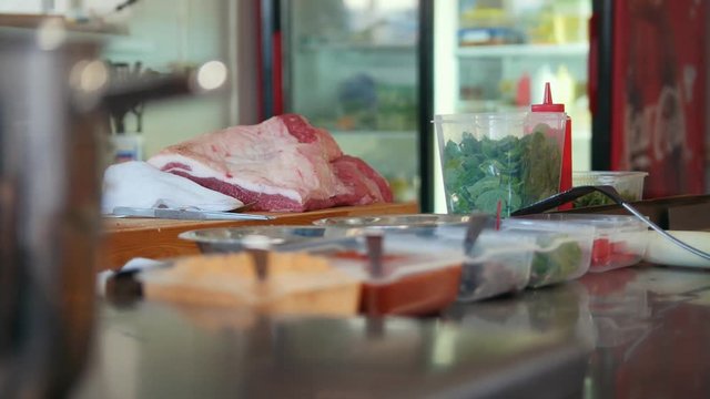 Commercial kitchen, meat and spices on the table ready to cook, pot on the stove