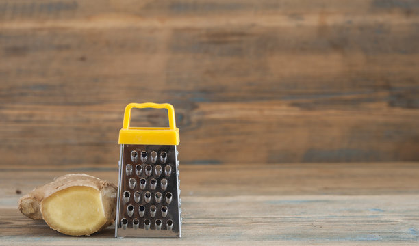 steel grater and ginger root on wooden table