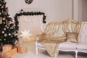 Luxurious sofa in a New Year's interior with a Christmas tree decorated with toys. Gold style.