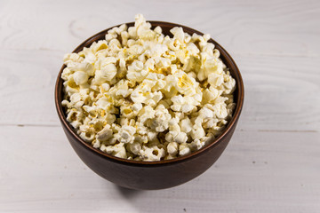 Bowl with popcorn on wooden table