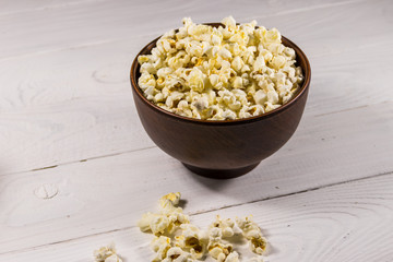 Bowl with popcorn on wooden table