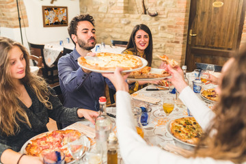 Friends eating pizza together and sharing platters