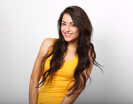 Beautiful positive happy woman in yellow shirt and long hair toothy smile on white background