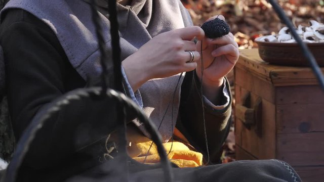 Close-up of a viking woman knitting in the forest camp