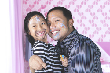 Father and daughter having quality time playing with face painting