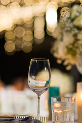 clear wine glass on table in dinner table with beautiful bokeh in background.