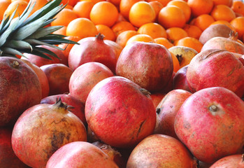 Heaps of various fruits on the market. Fruits of pomegranate and oranges.