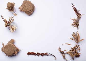 Autumn composition. Frame made of autumn leaves, buckthorn, a jar with burlap, pine cones on white background. Flat lay, top view, copy space.