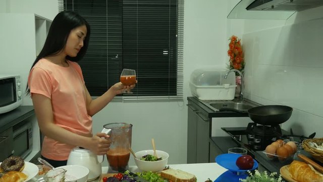 4k of young woman with smoothies in glass at kitchen room