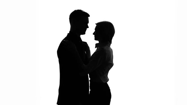 Silhouette of slim and fragile secretary tightly clinging to chest of her boss
