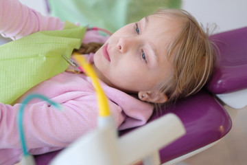 Obraz na płótnie Canvas A little girl is lying in an armchair at a reception near a dentist