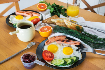 Homemade breakfast with fried egg toast sausage fruits vegetable beans coffee and orange juice. Delicious american breakfast for family.