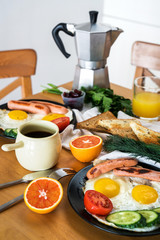 Homemade breakfast with fried eggs toast sausages fruits vegetables orange juice and coffee. Delicious homemade american breakfast concept for background.