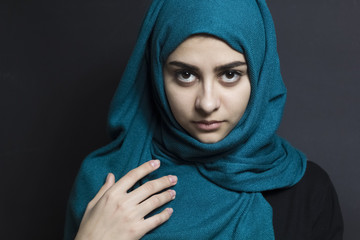 Portrait of a muslim girl in hijab with beautiful eyes on a black background. 