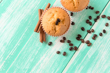 cupcakes with cinnamon sticks and coffee beans on a green wooden background