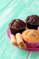 chocolate cupcakes with cookies on green wooden background.