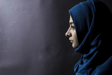 A Muslim girl on a black background. Copy space