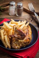 Roasted chicken with french fries on a plate.