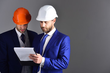 Architects with serious faces discuss project.