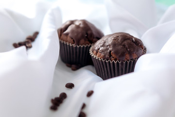 chocolate muffins with coffee beans on white fabric