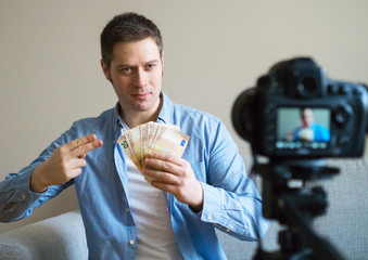 Handsome man making video blog about money earning.