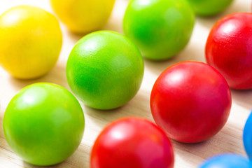 Colored pegs board, wood beads on wooden background. Shallow DOF