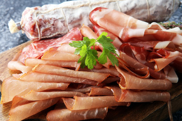 Food tray with delicious salami, pieces of sliced ham, . Meat platter with selection.
