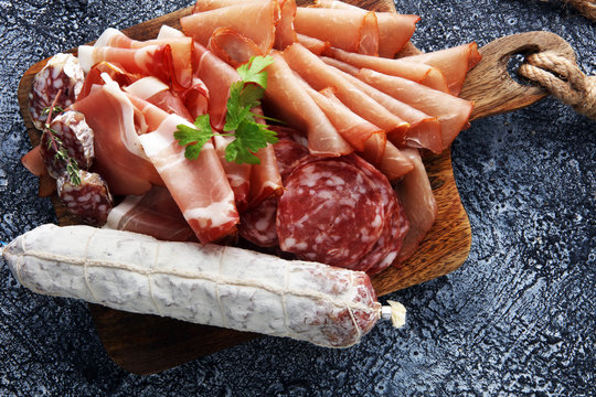 Food tray with delicious salami, pieces of sliced ham, . Meat platter with selection.