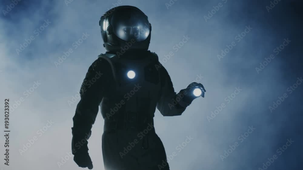 Poster courageous astronaut in the space suit holds flashlight and explores mysterious alien planet covered