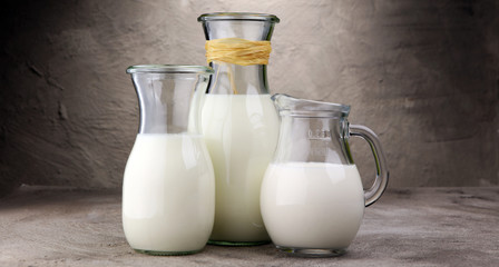 A jug of milk and glass of milk on a table