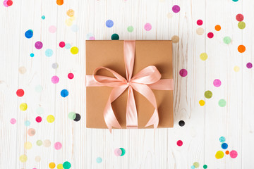 Gift box with pink ribbon on white background with multicolored confetti