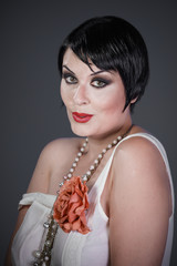 Brunette girl with short hair, French mane in the style of the 20s. She wears white fur coat and...