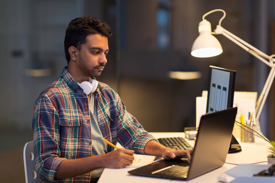 creative man with laptop working at night office