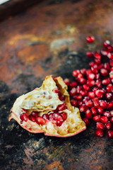 Pomegranate fruit and pomegranate seeds over rustic background.