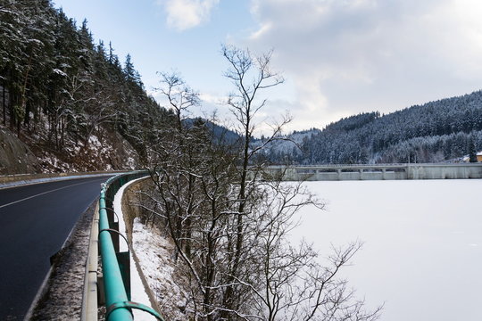 Concrete Brezova dam with hydroelectric power plant and road to Karlovy Vary, snowy winter day, Czech Republic