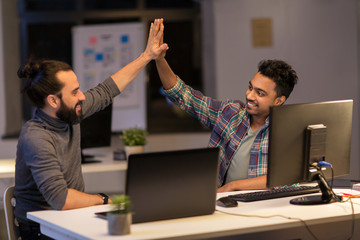 creative team making high five at night office