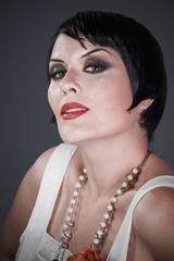 Brunette girl with short hair, French mane in the style of the 20s. She wears white fur coat and...
