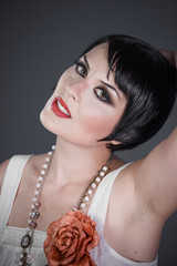 Brunette girl with short hair, French mane in the style of the 20s. She wears white fur coat and...
