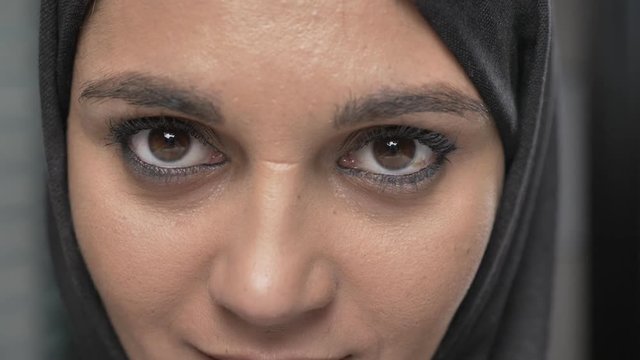 Young beautiful girl in black hijab looking at camera. Portrait, close-up of eyes 60 fps