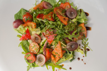 Tasty vegetarian salad top view. Fresh salad of arugula, bell pepper, cherry, grape on plate