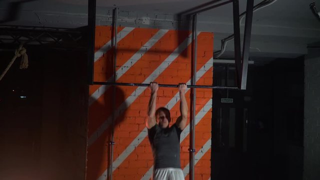 the athlete makes pull-ups with a back grip on the horizontal bar in the gym