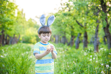 Kid on Easter egg hunt in blooming spring garden. boy searching for colorful eggs in flower meadow