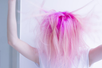 pink hair woman is roughing her hair by hands in the air