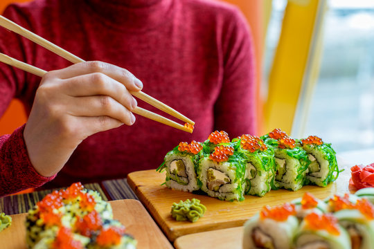 Woman eating sushi rolls at the table