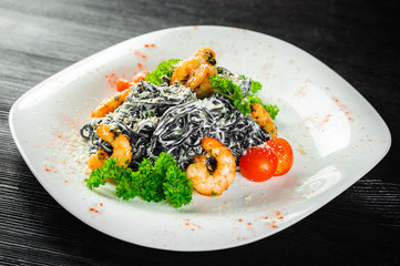 Black pasta with shrimp and seafood on a black wood background